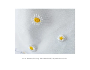 Close-up of intricate white lace mesh fabric with detailed yellow daisy embroidery