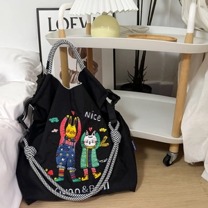 Close-up of black nylon tote bag featuring cartoon animal embroidery and houndstooth strap