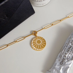 Elegant 18k gold plated titanium necklace with sunburst zircon pendant on white surface