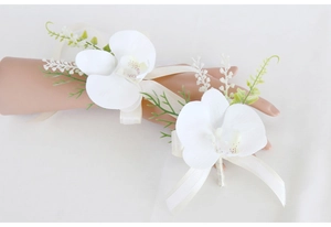 Detail of white orchid wrist corsage and boutonniere set with silk ribbons for weddings
