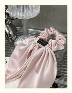 Detailed view of pink satin bow hair scrunchie with long ribbons and handmade label
