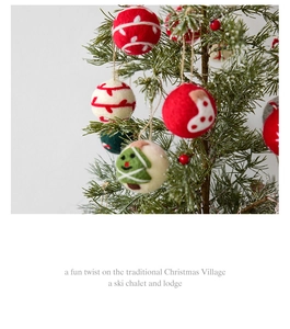 Close-up of handmade wool felt Christmas balls with festive patterns on pine branches