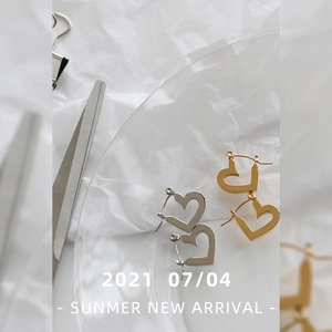 Detail of hollow heart stud earrings in gold and silver finish with tassel chain