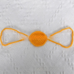 Macro shot of bright yellow handmade crochet nose ornament with knitted yarn texture