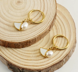 Detail of shell dangle earrings with drop pearl on rustic wooden display blocks