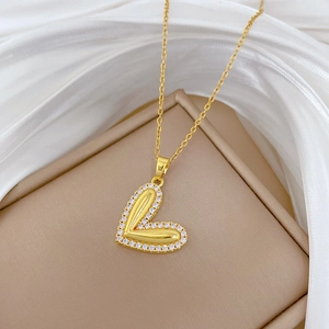 Close-up of golden heart pendant with sparkling crystals on a white silk background