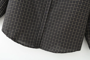 Close-up of curved hem and button placket on dark plaid casual button-down shirt