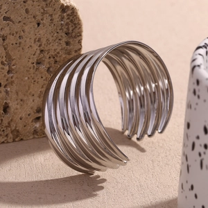 Close-up of polished silver multi-layer open cuff bracelet set against a textured stone