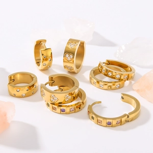 Golden stainless steel heart and zircon earrings displayed with decorative crystals