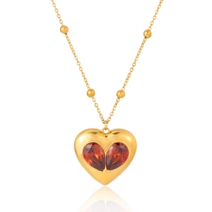 Vue détaillée d'un collier pendentif cœur doré orné de zircons rouges taille poire