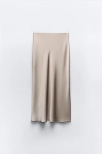 Detailansicht des champagnerfarbenen Satin-Midirocks mit seidiger Textur und Lichtreflexen