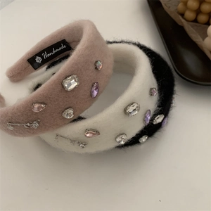 Detail of plush headbands in pink and white with sparkling rhinestones and metal accents