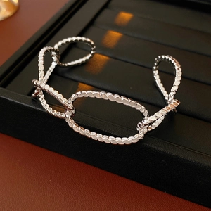 Macro shot of silver-tone hollow chain bracelet with twisted spiral texture on leather