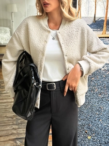 Detail of cream sherpa baseball jacket with snap buttons and ribbed cuffs on model