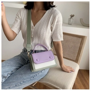 Detail of color-block flap bag with purple and mint green panels on a rattan chair