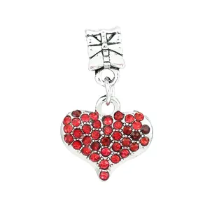 Macro shot of silver heart charm with red rhinestones and a delicate bow clasp