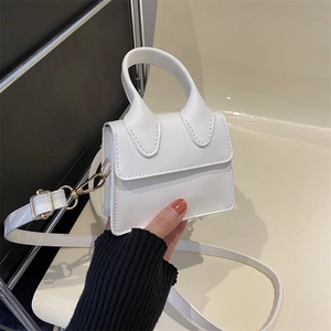 Mini white leather crossbody bag with adjustable strap shown in a modern hand-held pose