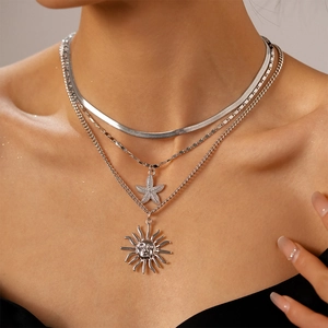 Close-up of a triple-layered silver necklace with starfish and sun face relief pendants