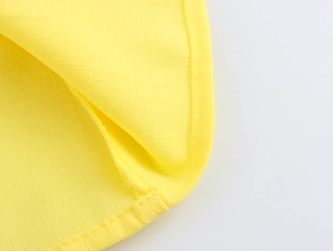 Macro shot of yellow fabric texture with precise stitching detail on shirt hem