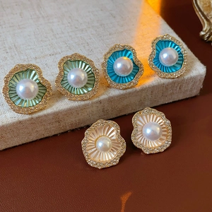 Détail de trois paires de boucles d'oreilles perles en forme de coquillage bordées d'or