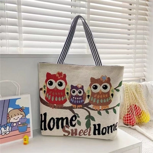 Detail of knitted tote bag with owl pattern and Home Sweet Home text on shelf