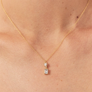 Macro view of gold chain featuring a square blue zircon pendant worn on a female neck