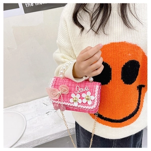 Girl's pink tweed handbag with pearl handle and bow shown worn by a model