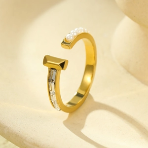 Close-up of gold titanium steel open ring with pearls and baguette-cut gemstone inlay