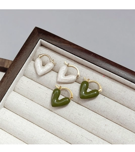 Close-up of heart-shaped enamel hoop earrings in pearl white and olive green on a jewelry box