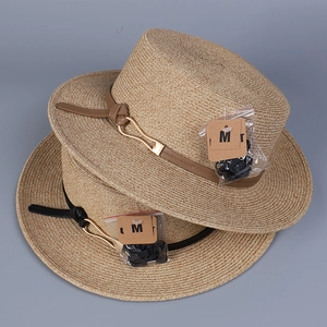 Détail de chapeaux en paille tressée avec bandes en cuir et boucles métalliques