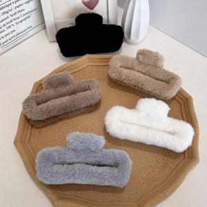 Plush faux fur oversized hair claw clips in neutral tones for women on a wooden tray