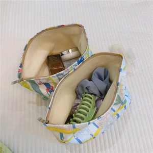 Close-up of floral print canvas makeup bags with metal zippers on white bedding