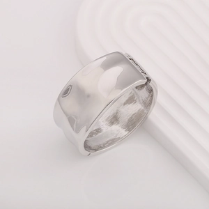 Detailed macro view of silver wide cuff bracelet featuring unique hammered liquid metal texture