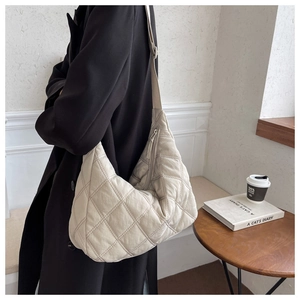 Detail of beige quilted nylon hobo bag featuring adjustable strap and puffer design
