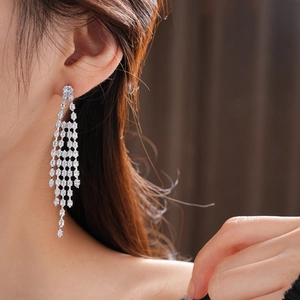 Close-up of silver tassel earrings with zircon stones worn by a model for elegant look