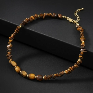 Macro detail of natural tiger eye stones and black agate beads on gold chain necklace