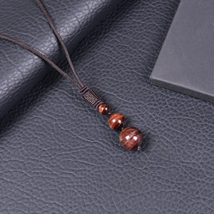 Close-up of three tiger eye beads on an adjustable brown braided necklace cord