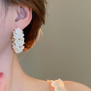 Close-up of white pearl flower cluster C-shaped earrings worn on the earlobe