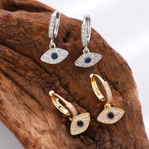 Detailed macro view of gold and silver evil eye hoop earrings with zircon on wood