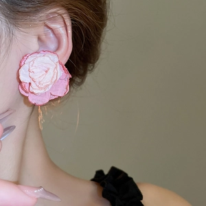 Handmade woven lace flower clip-on earrings in pink and cream on a model