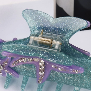 Macro detail of turquoise glitter starfish hair claw clip with inlaid rhinestones