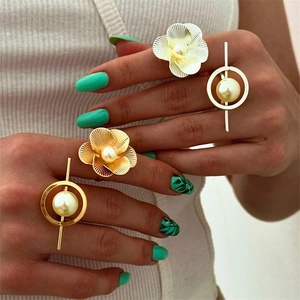 Detail of chunky floral and geometric rings with pearls worn by a fashion model