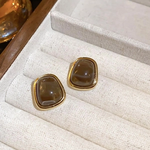 Macro detail of retro round gold earrings with brown stone in a jewelry box