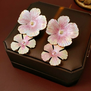 Detail view of pink gradient enamel flower earrings with golden edges on jewelry box