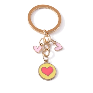 Golden metal keychain with pink heart charms and yellow round pendant on white background