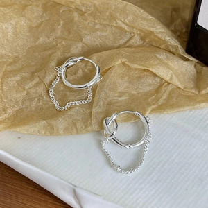 Detailed view of silver hoop earrings with chain link accents on textured paper