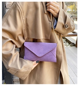 Detail of purple faux suede envelope bag with elegant golden metal chain strap