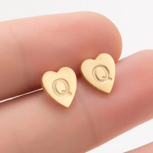 Gros plan d'une boucle d'oreille cœur en or avec gravure Q et finition mate brossée