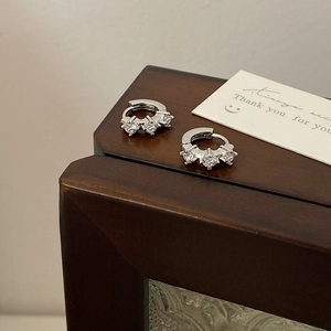 Detailed view of silver hoop earrings featuring three sparkling round-cut cubic zirconia