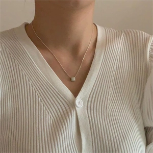 Close-up of a 925 sterling silver necklace with a square cubic zirconia on a model